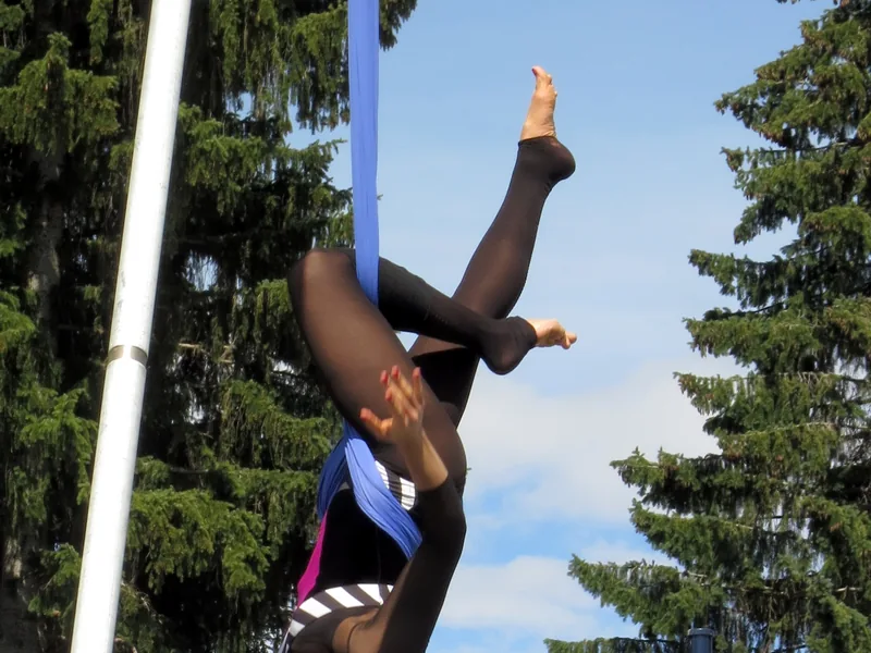 Legs and blue silks of an aerial performer against the sky